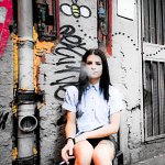 Tattooed girl smoking in alleyway.
